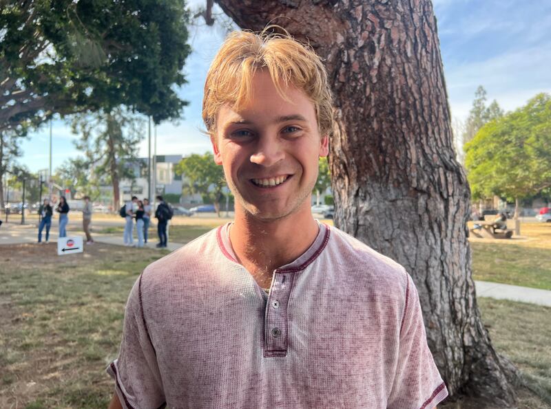 A smiling man with light hair and a pink shirt.