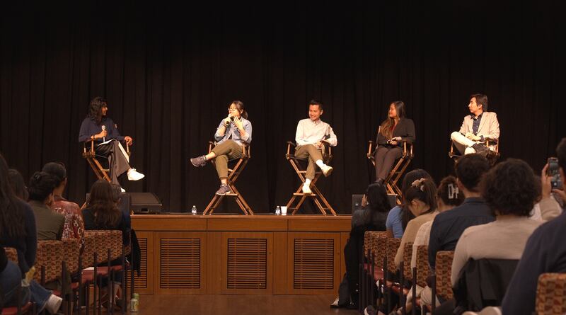 Photo of five people speaking on a stage