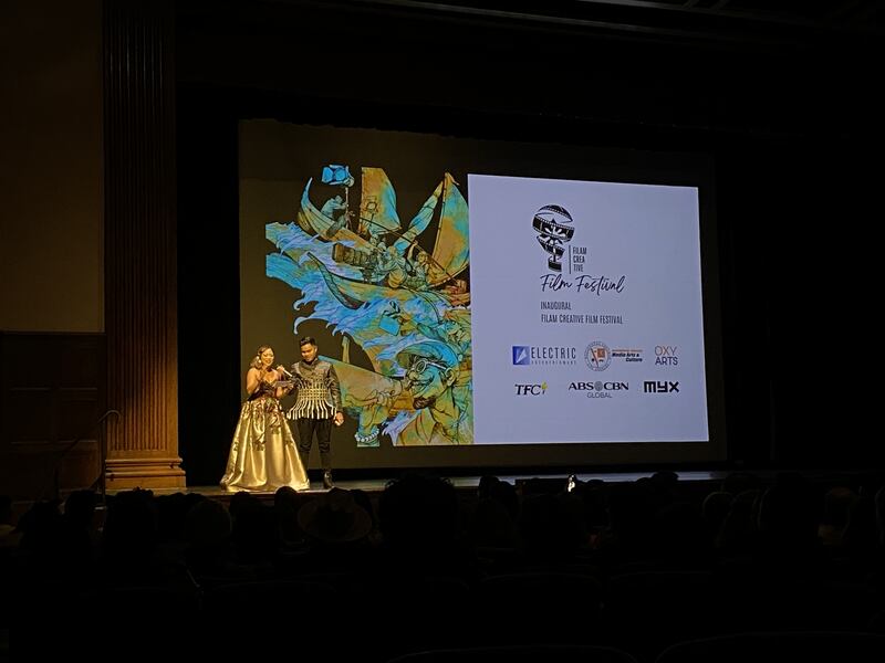 Two people stand on stage at a film festival.