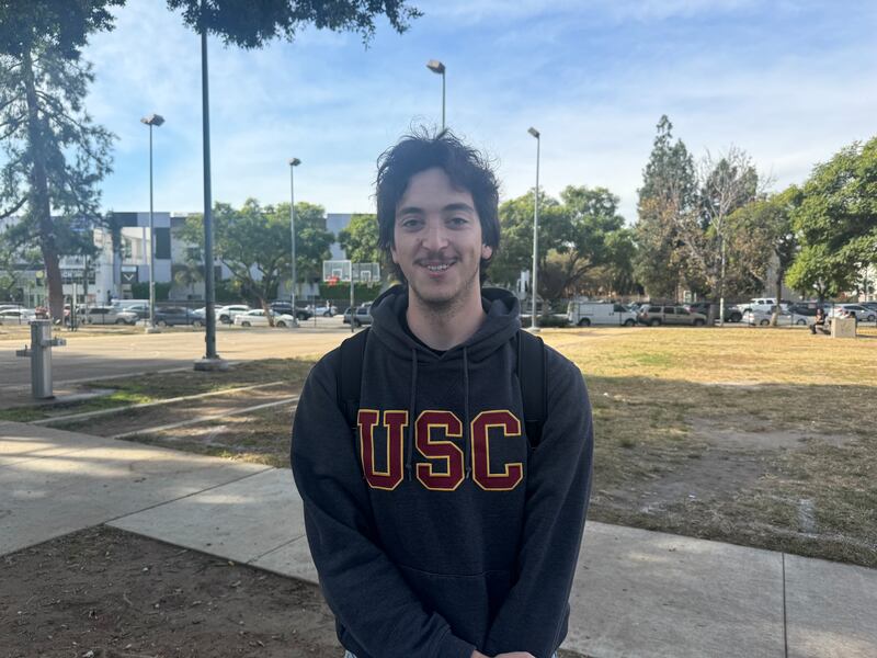 A man in a USC sweatshirt standing on a lawn.