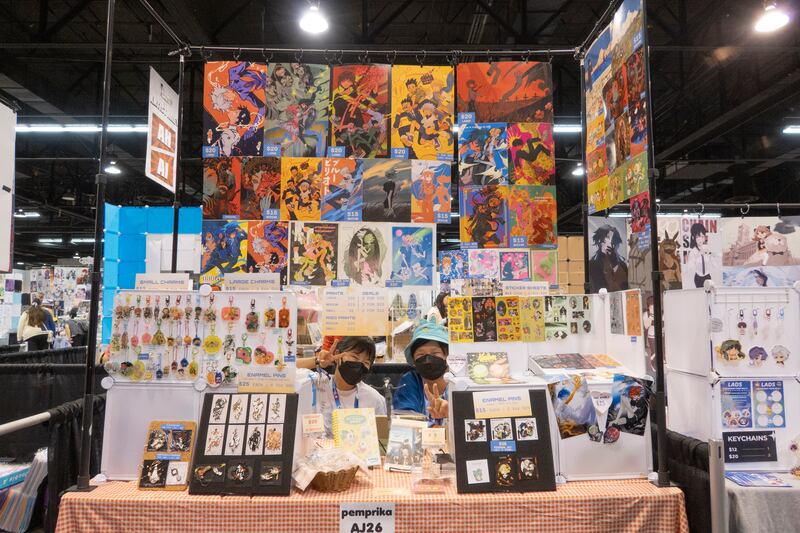 Artist pose for the camera with their booth