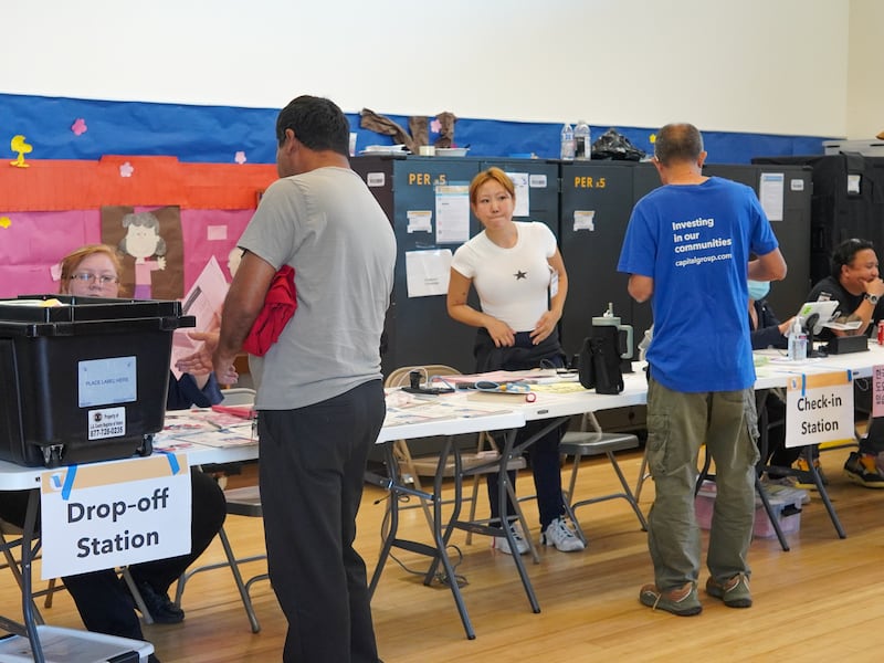 Voters stand in front of the polling station at the Chinatown Public Library in Los Angeles to submit their ballots.