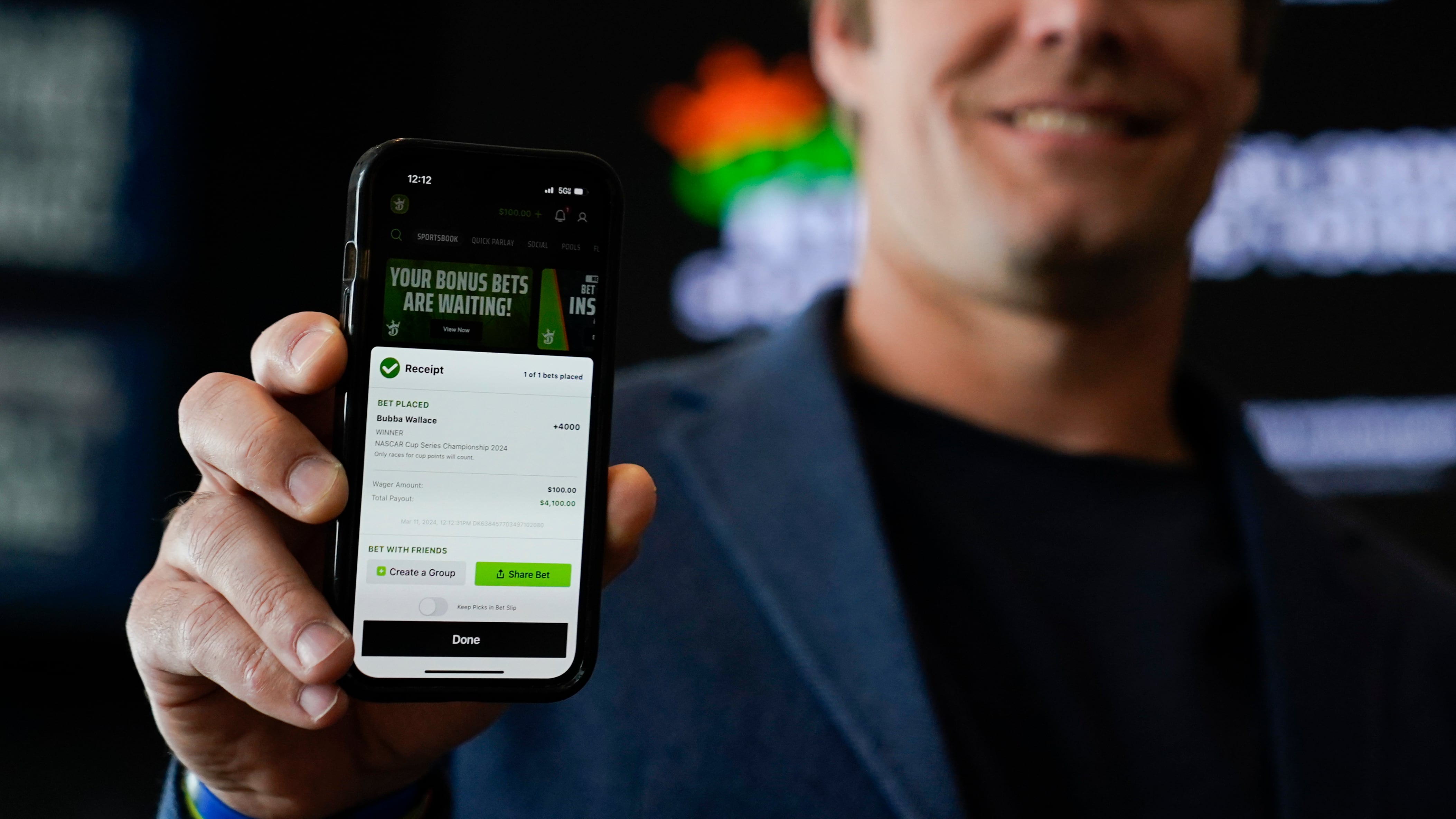 A picture of former NFL tight end Greg Olson holding his phone to show a DraftKings receipt of a sports bet he placed.