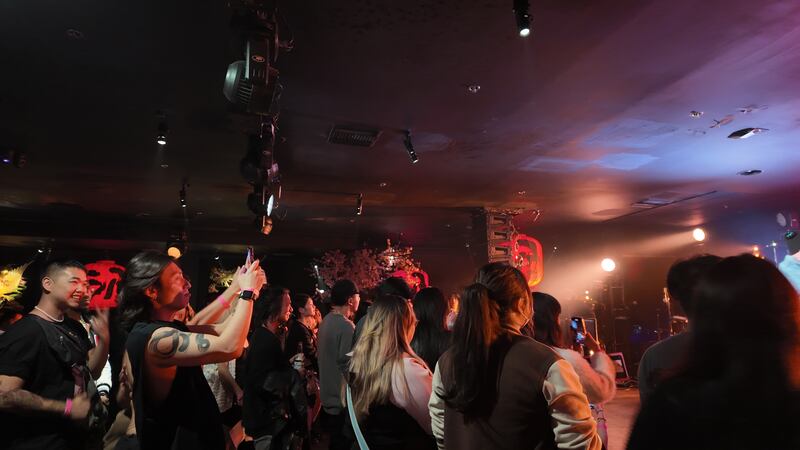 Photo of a group of people in a room in front of a stage with spotlights