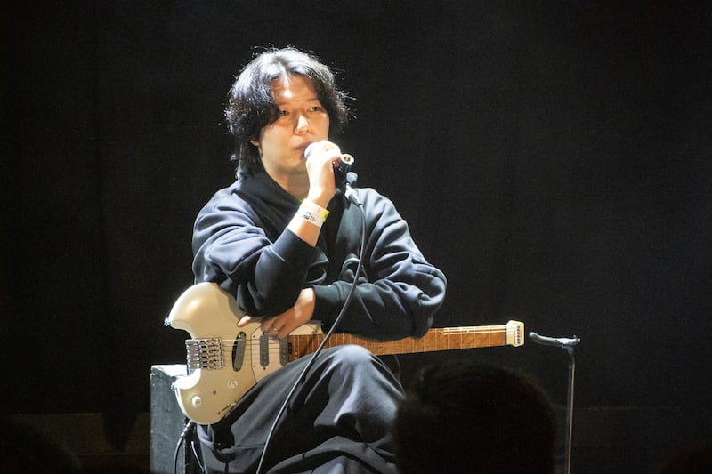 Guitarist talks into a microphone.