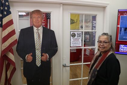 Rachel Gunther, LA GOP Grassroots Coordinator and Trump supporter since 2016 stands next to a cardboard cutout of Former President Trump.