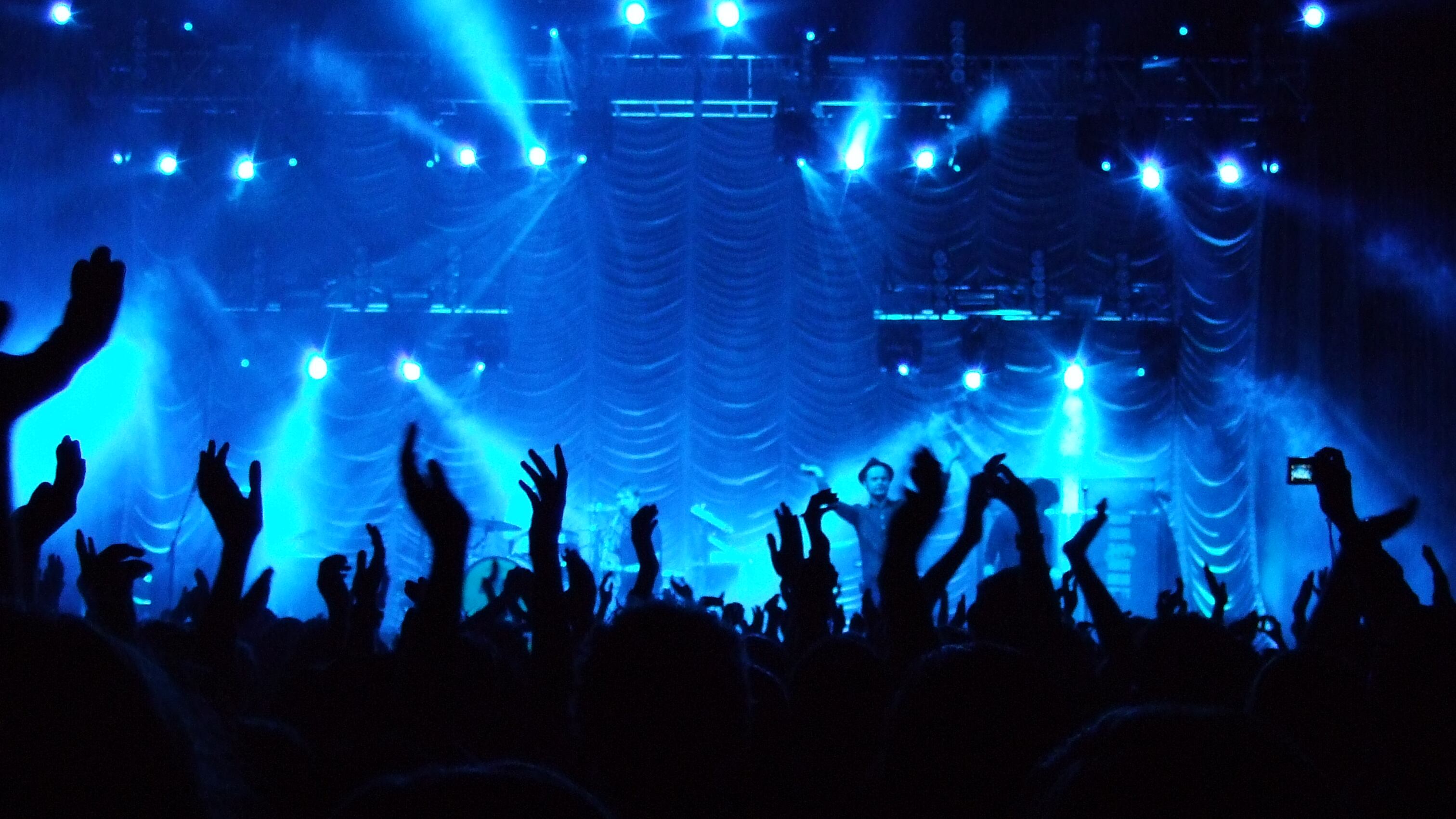 A photo of a crowded concert with blue lights in the background.