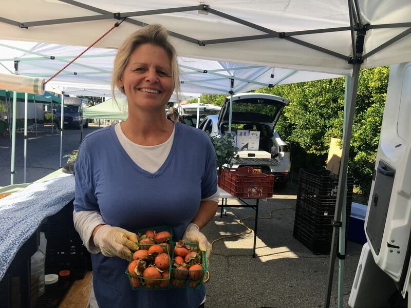 Julie Behneman holds baskets of persimmons at the Santa Monica Farmers Market.