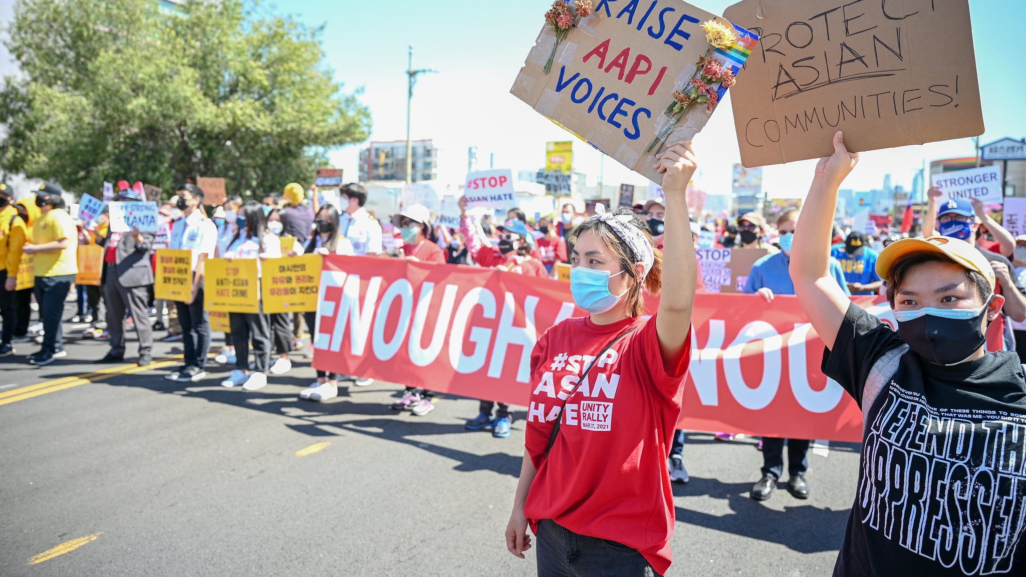 Demonstrators at a Stop Asian Hate rally in L.A.'s Koreatown on March 27, 2021. A group of people are holding a banner saying "ENOUGH IS ENOUGH" and two people at the front are holding signs saying "RAISE AAPI VOICES" and "PROTECT ASIAN COMMUNITIES."