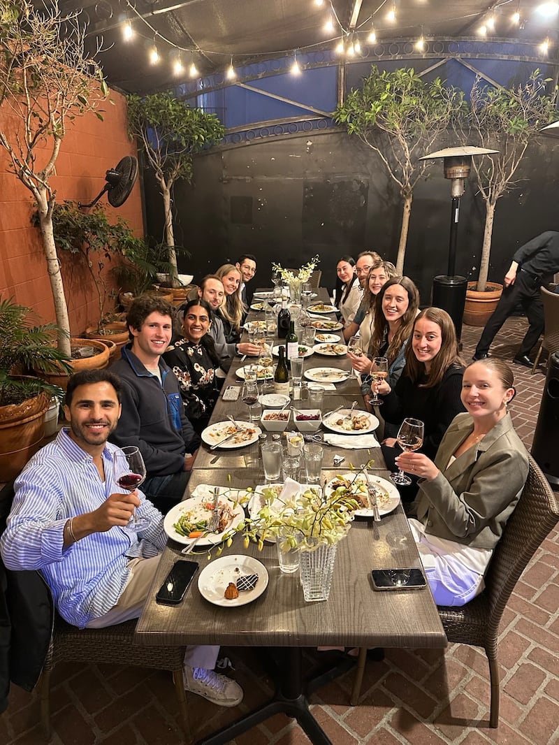 People sit at a long table with plates of food in front of them.