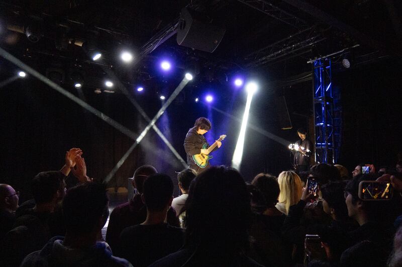 Lights beam down on a guitarist.