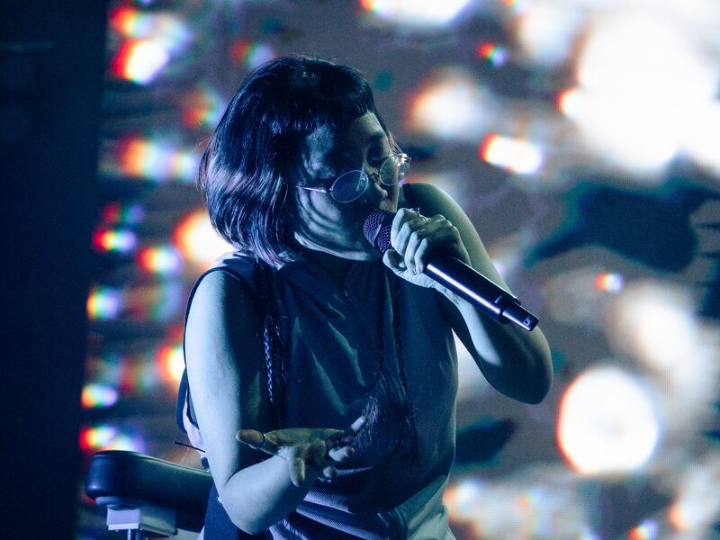 Photo of a woman in front of scattered white lights singing