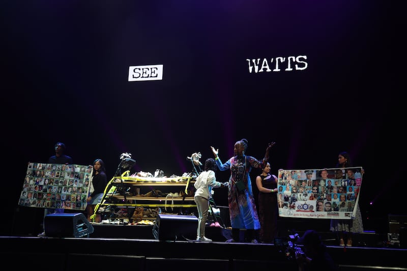 Before the screening begins, filmmaker Lawanda Hawkins joins community members on stage, holding up photos of children lost to violence. Beside them, pairs of shoes from Hawkins’ powerful installation Silent March serve as a solemn tribute to the innocent lives taken and a reminder of the community’s ongoing call for peace.