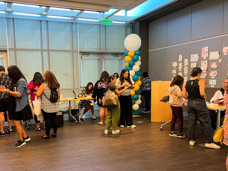 Photo of a hall with balloons, tables and people walking around