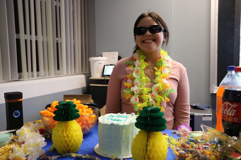 A photo of Tess smiling in front of cake and decor.