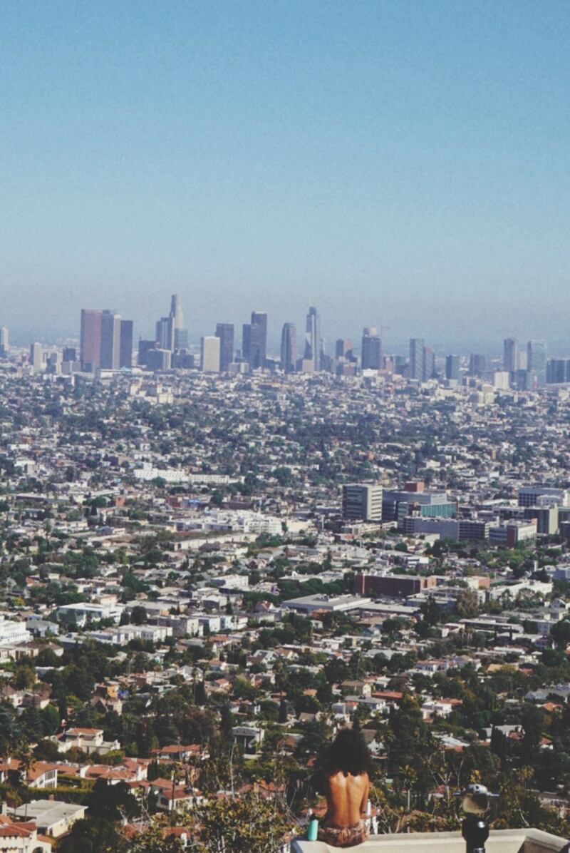A man looks out at Los Angeles covered in a fine layer of smog.