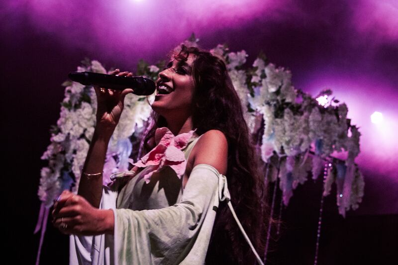 Photo of a woman singing in front of a tree prop