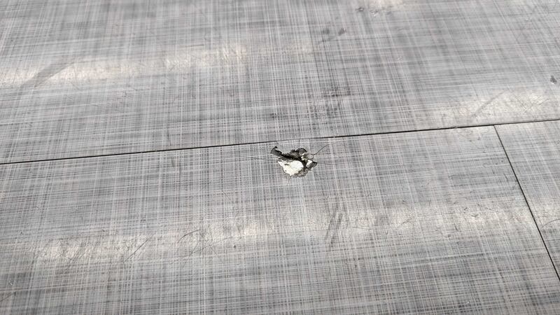 Photo of a tile floor with a small hole with cracks spreading out of it