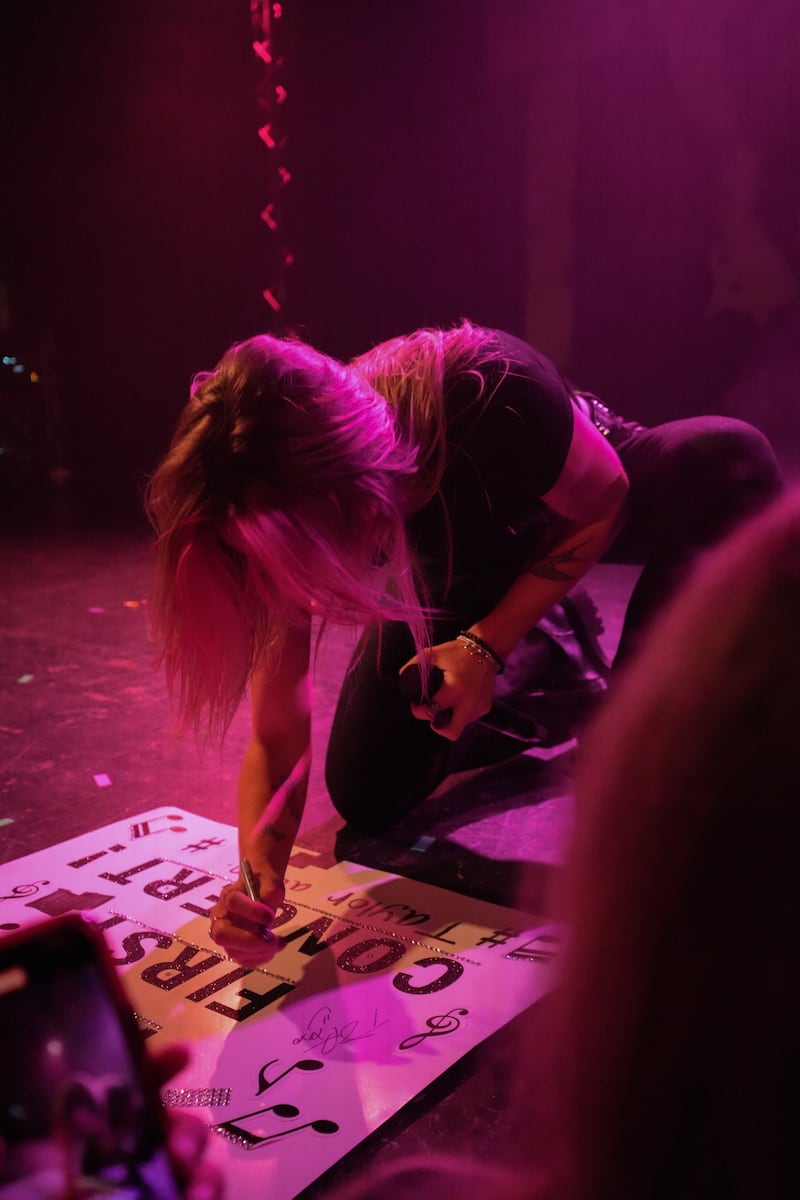 Artist signs poster.