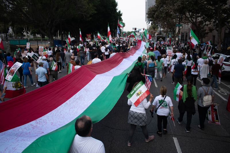 Messages are written along an Iran flag that is carried through the streets with some of the phrases being “Free Iran”, “For Freedom” and “IRGC Terrorist.”