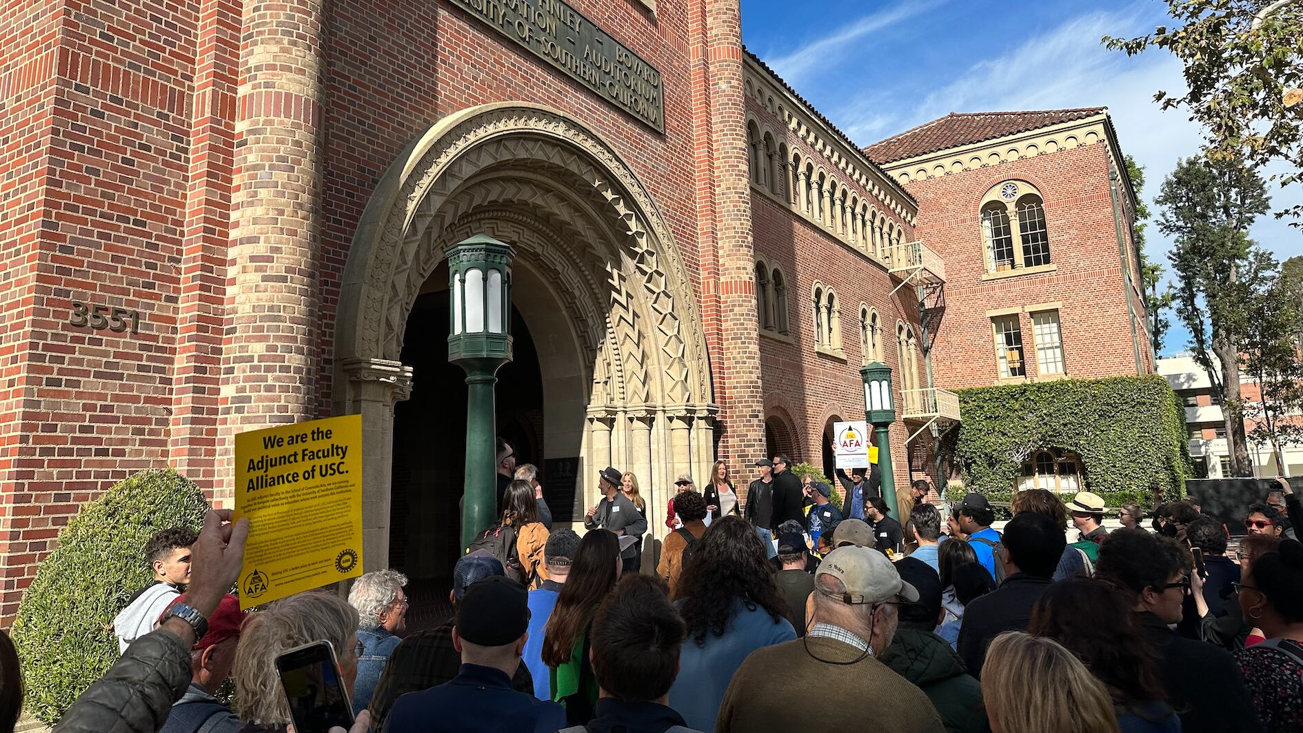Adjunct professors at the USC School of Cinematic Arts march outside Bovard Auditorium.