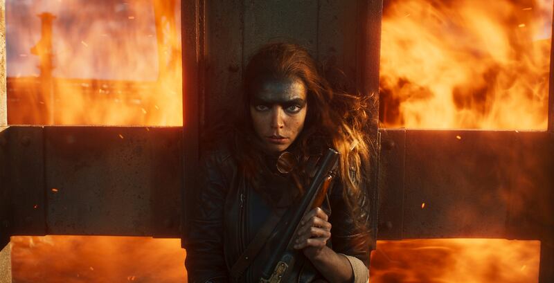 Film still of a woman with a gun in front of fire