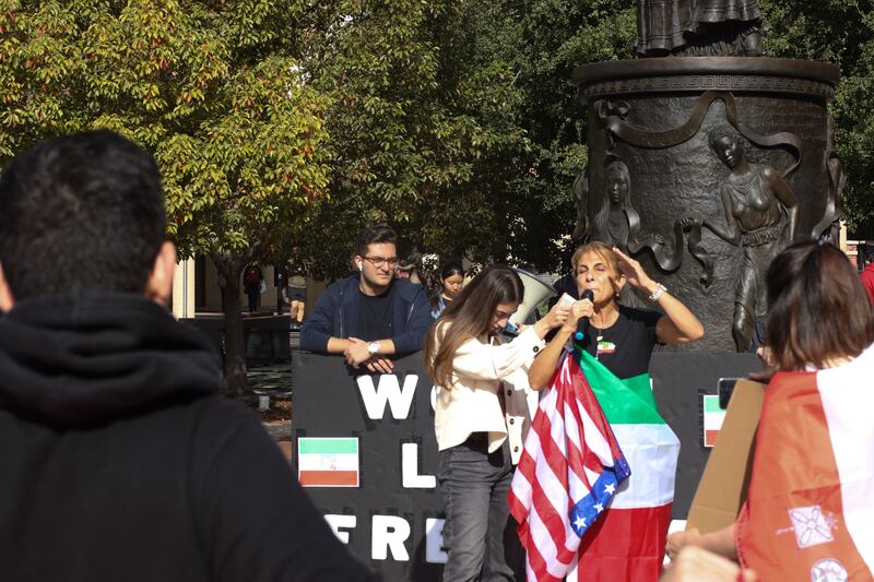 Woman stands in front of Hecuba statue, delivering a speech