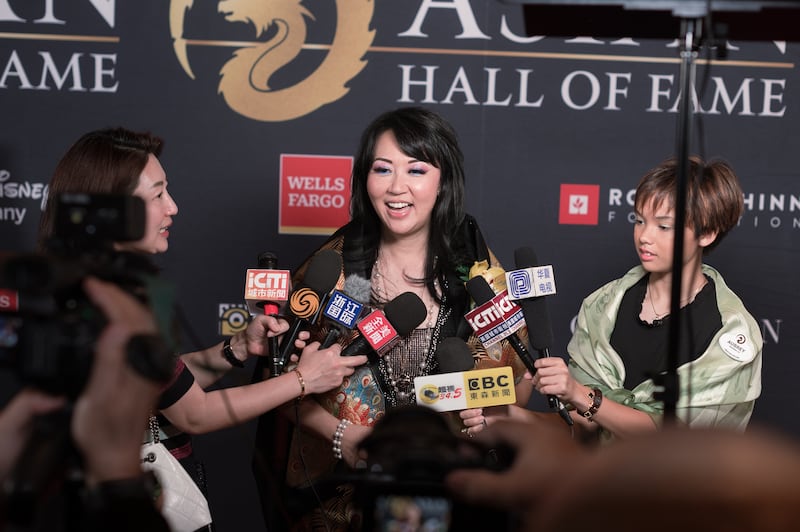Photo of a woman with several microphones held in front of her