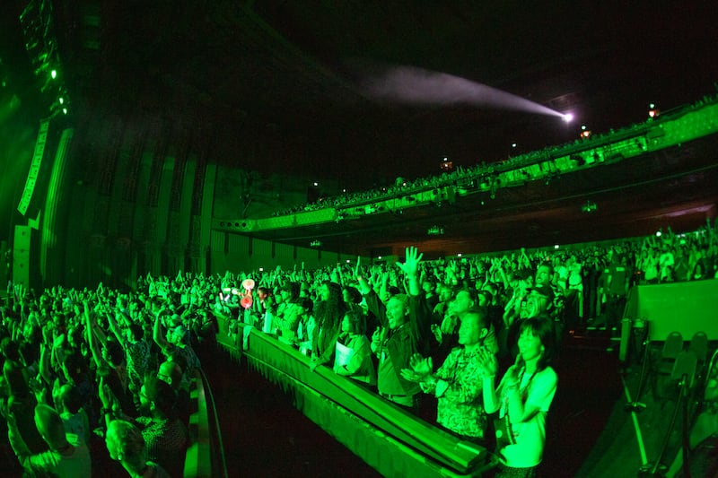 Photo of a large crowd with green lights shining over it