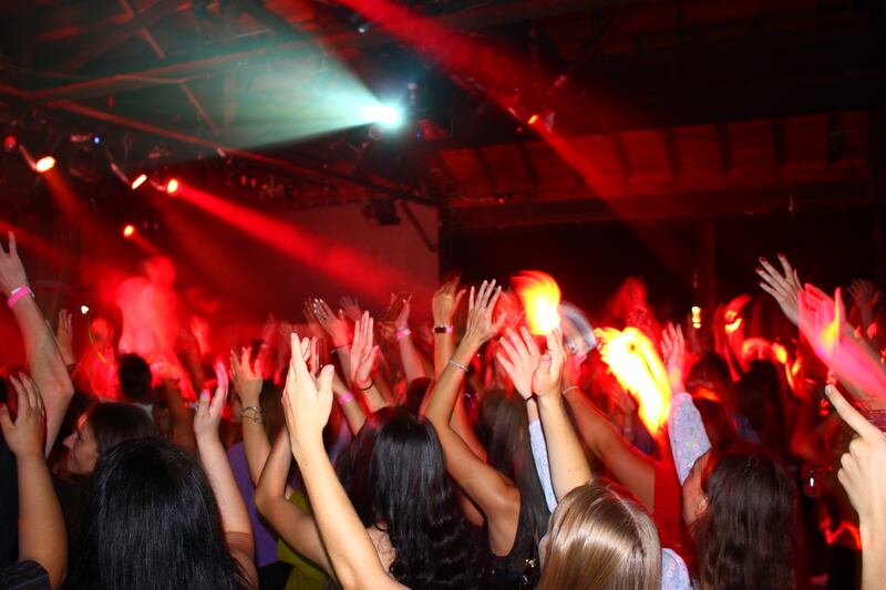 All hands of the crowd wave along to the music as a red light strobes.