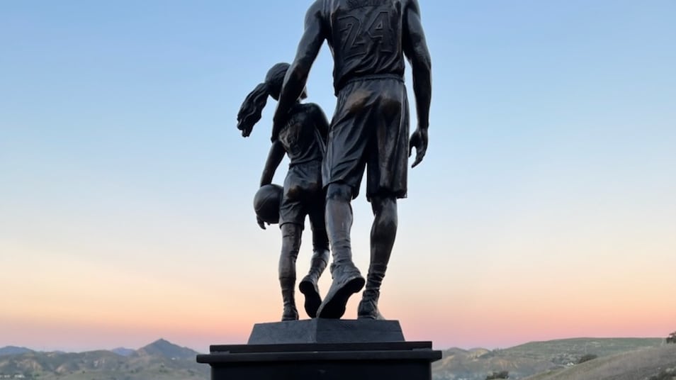 "A photo of a sculpture of Kobe and Gianna Bryant at sunset."