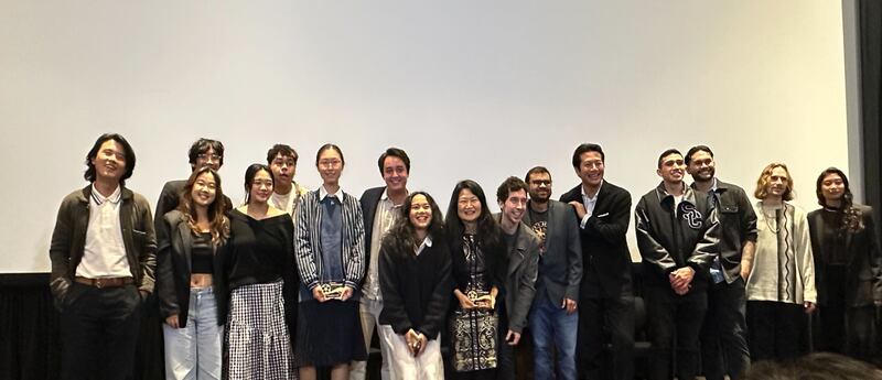 Photo of a group of people posing in front of a blank screen