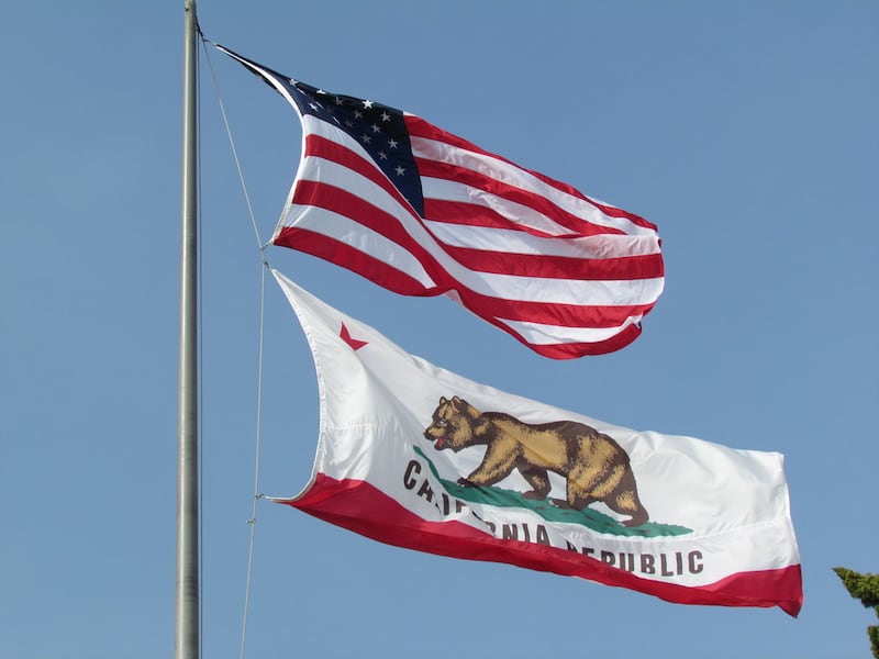 The United States flag and the California state flag hanging together on a flagpole.