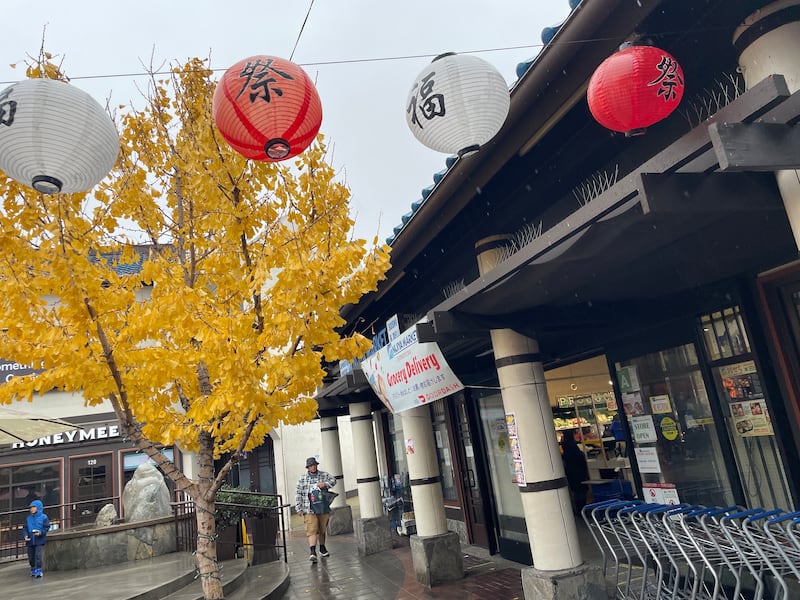 Photo of lanterns hanging over a sidewalk in front of a supermarket