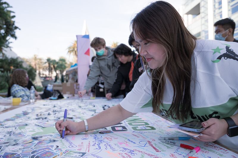 Ashley Kim, a senior at USC studying theatre, signs a fanboard outside the Anaheim Convention Center Arena. The Houston native wore a Houston Outlaw jersey to catch the games. (Photo by Michael Chow)
