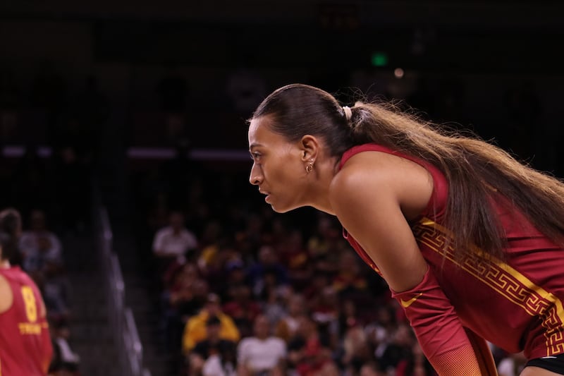 Faumuina in profile with hands on knees wearing cardinal USC volleyball uniform with gold accents.