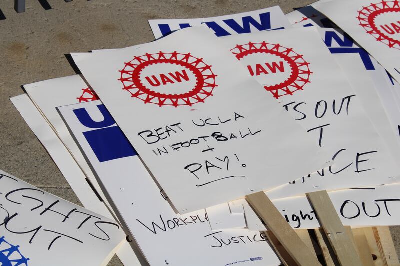 Photo of UAW sign that reads, "Beat UCLA in Football + Pay"