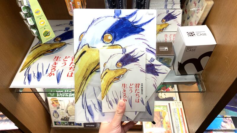 Photo of a hand holding posters and fliers with a bird on it