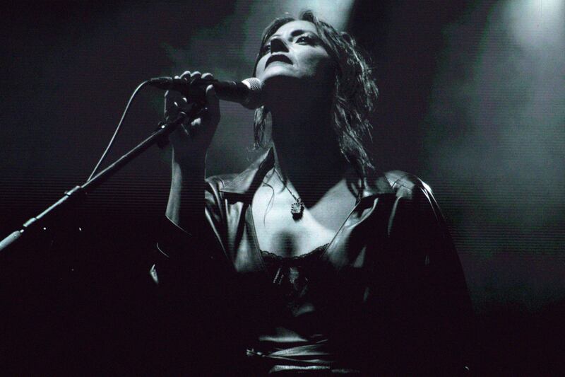 Black and white photo of a woman singing on a large screen