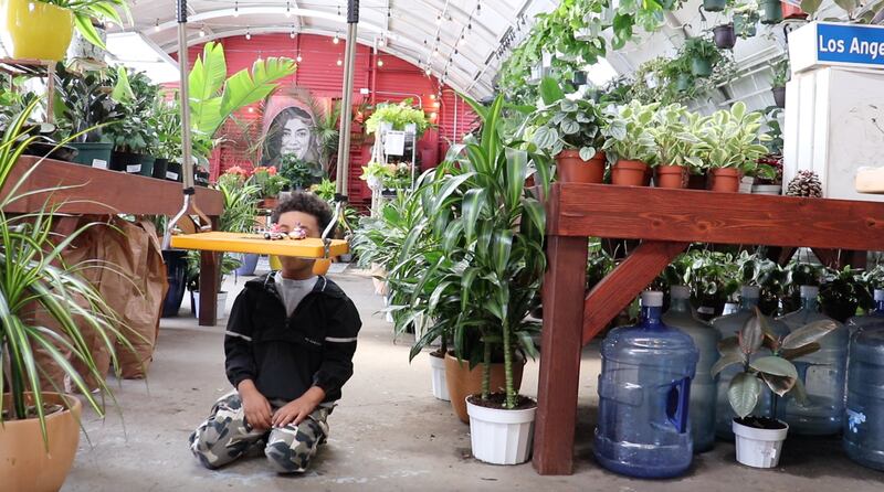 "A photo of a little boy playing with toy cars on a swing set in The Plant Chica nursery."