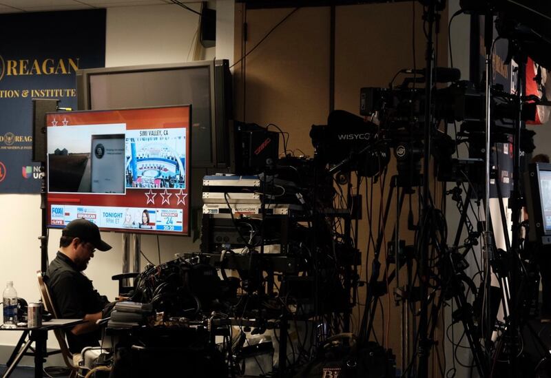 A member of the press sits behind his gear in the spin room.