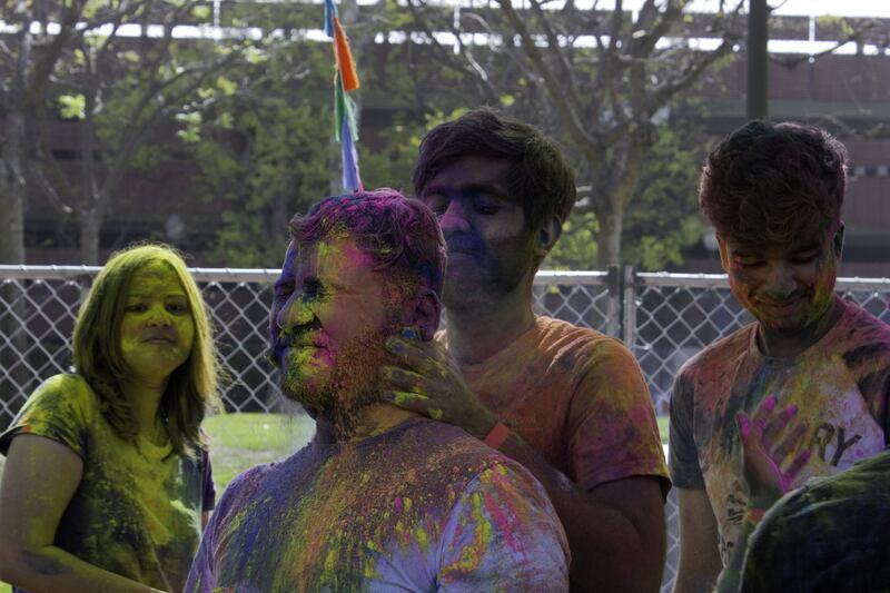 A student grimaces as his face gets smeared with colors by his friend.