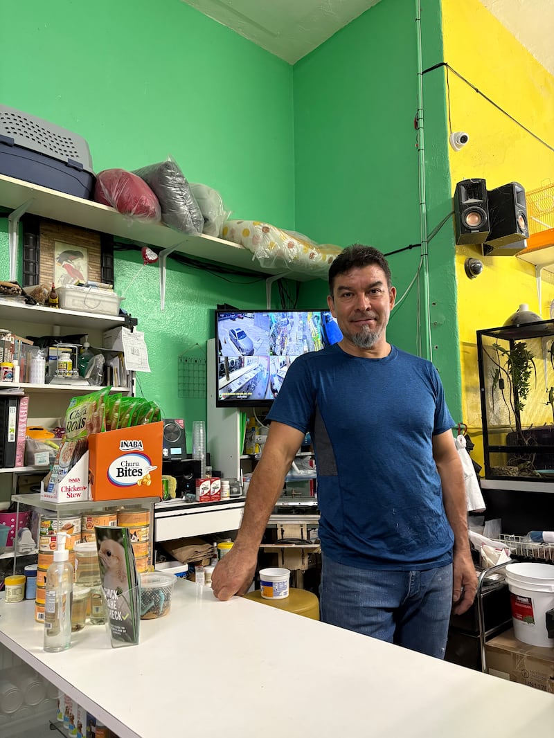 Photo of a man posing at a counter. A television can be seen behind him