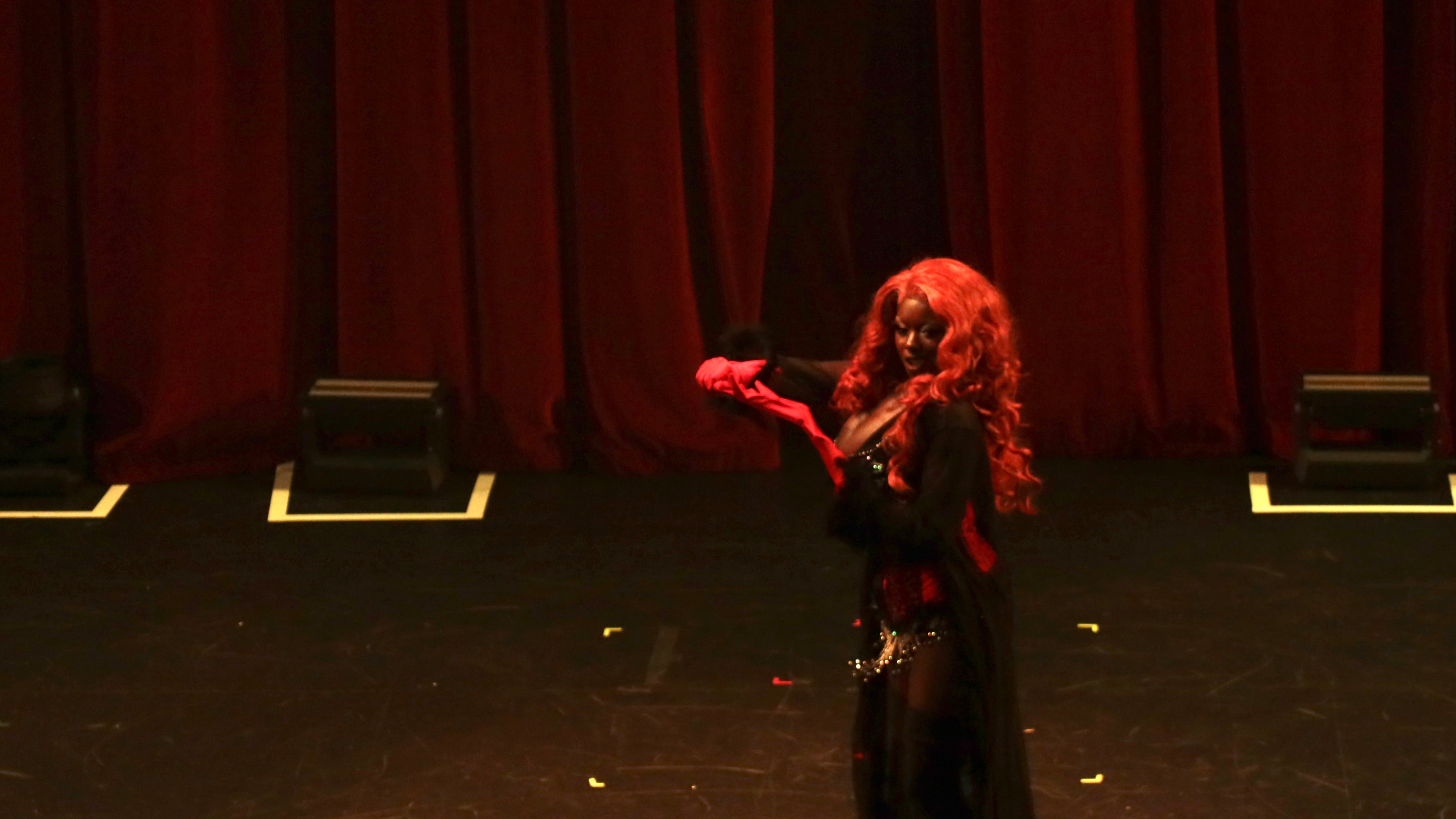 Student performer May Glove on stage holding a heart.