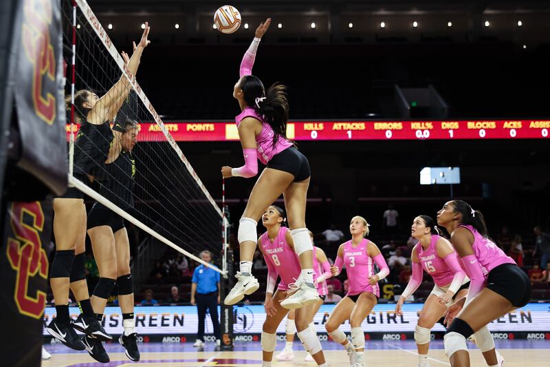London Wijay rises up above the net to slam a volleyball against two jumping Oregon defenders.