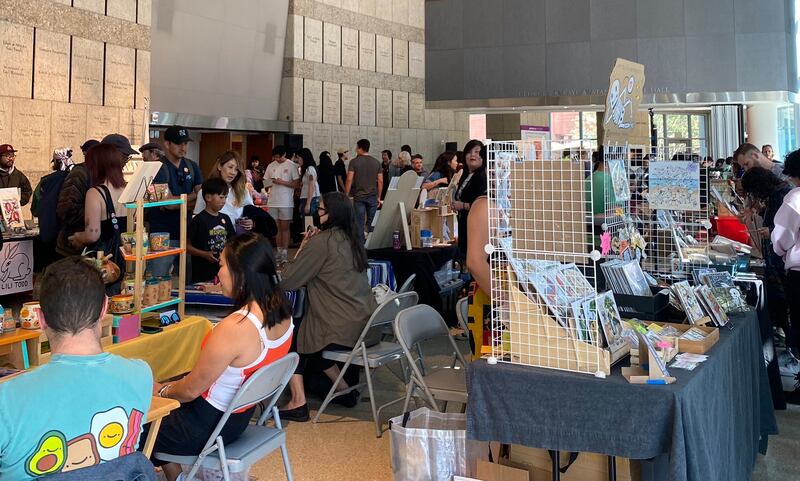 Photo of a crowd of people walking through rows of booths with art