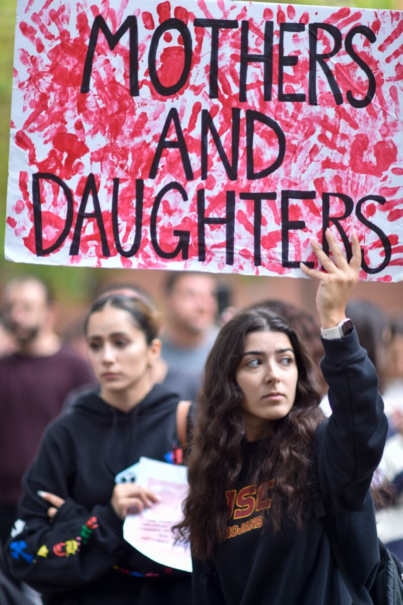 Protestor holding "Mothers and Daughters" sign