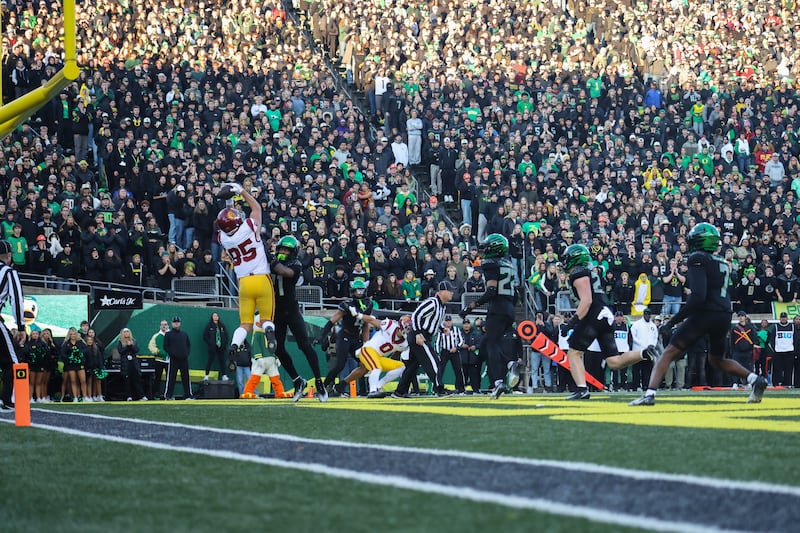Walker Lyons (85) rises up in the endzone to attempt a catch. He is guarded tightly by an Oregon defender.