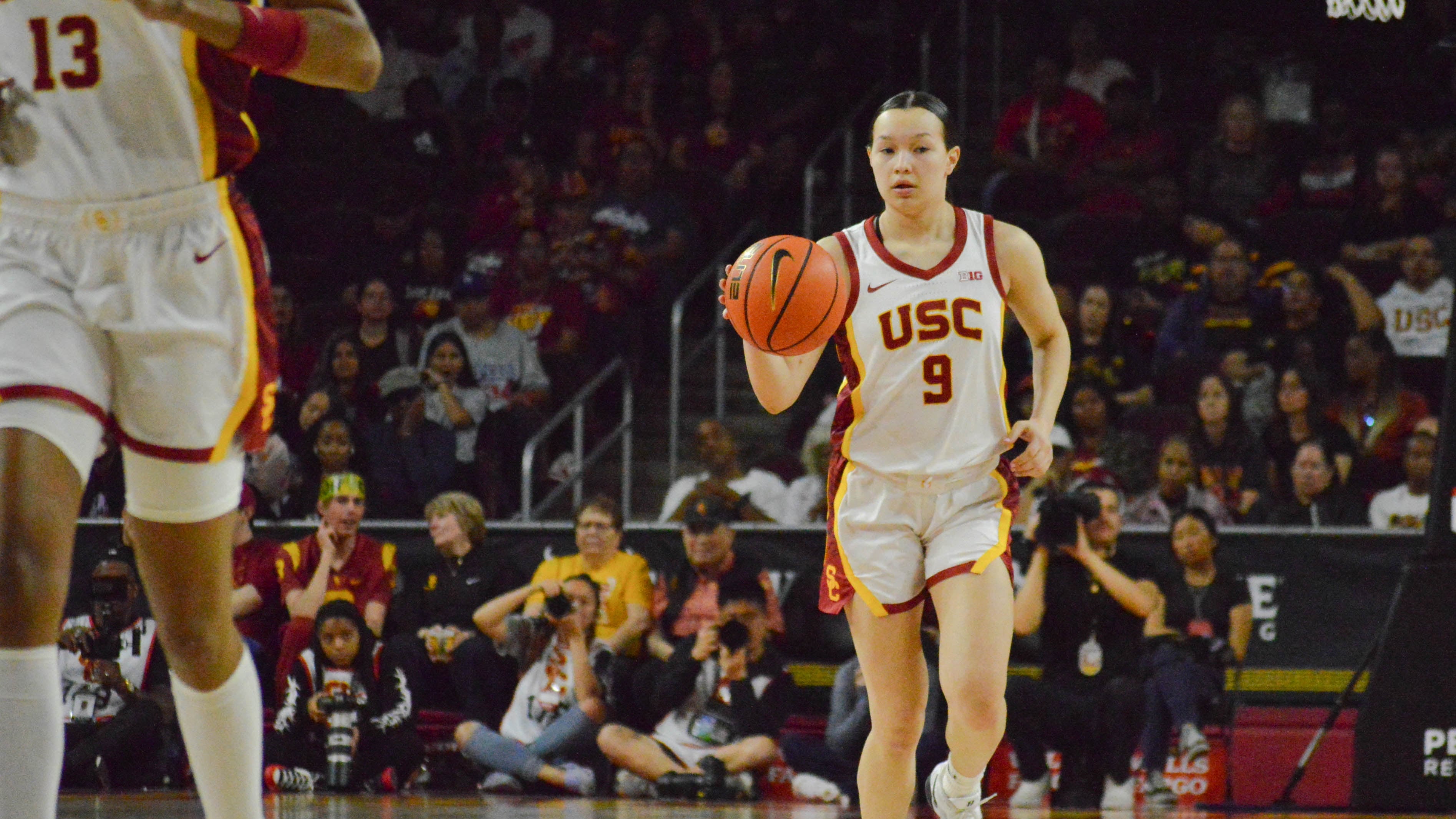 Kayleigh Heckel, wearing a white No. 9 jersey, is pictured dribbling up the court with her right hand.