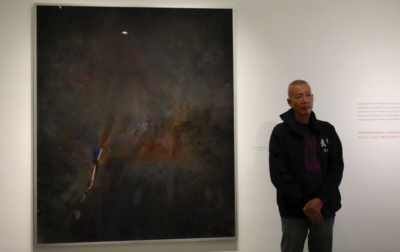 A person standing beside his painting